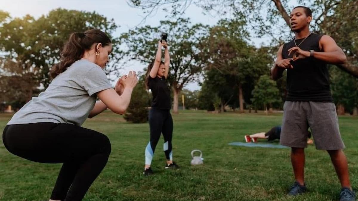 Personal trainer coaching strength exercises outdoors