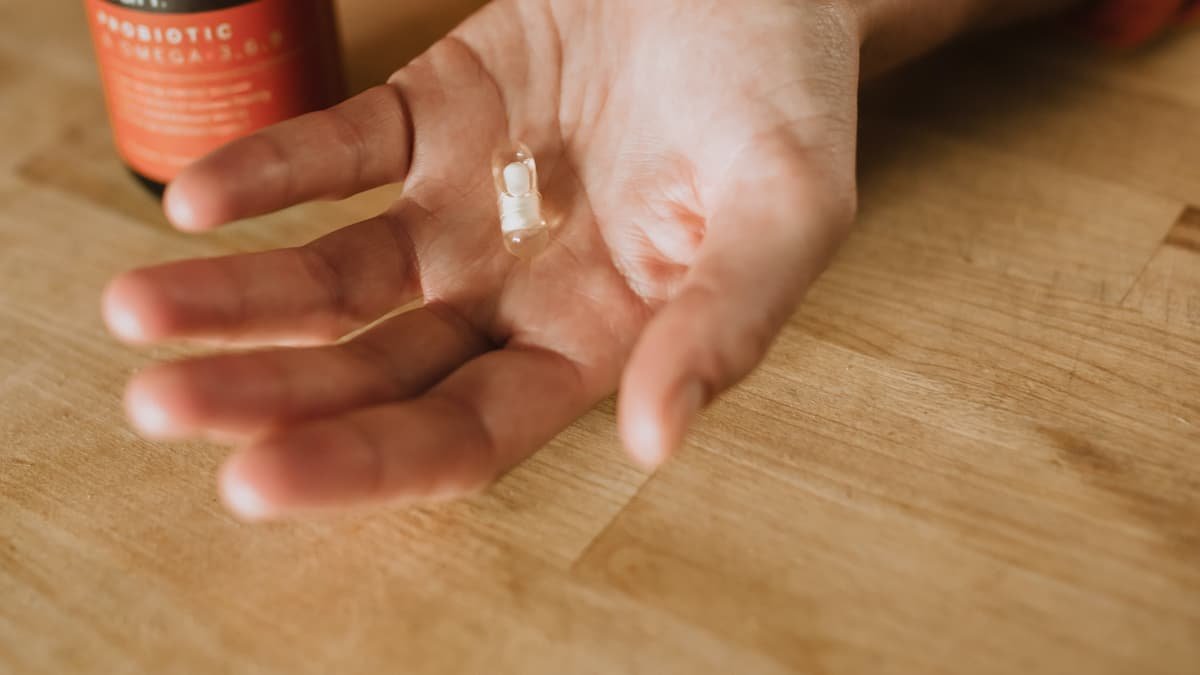 Person holding a probiotic supplement capsule in their hand, symbolising gut health support.